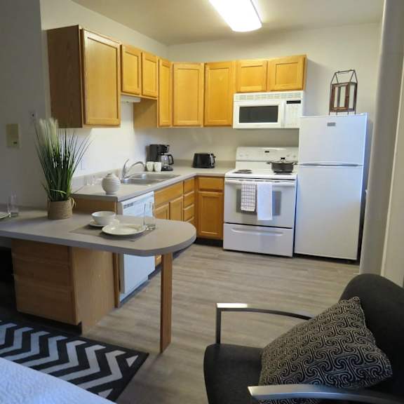 A kitchen with a white refrigerator and wooden cabinets.