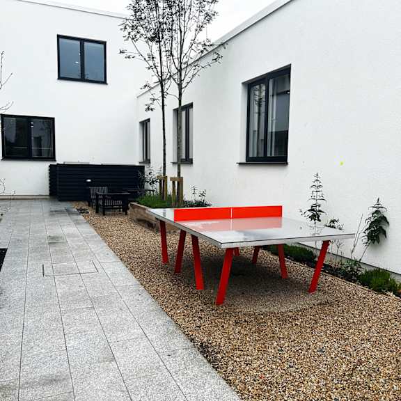 A red and white table is in front of a white building.