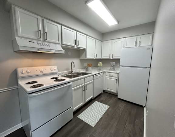 A white kitchen with a stove, sink, and refrigerator.