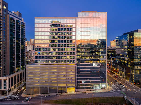 A modern glass building with a parking garage in front of it.