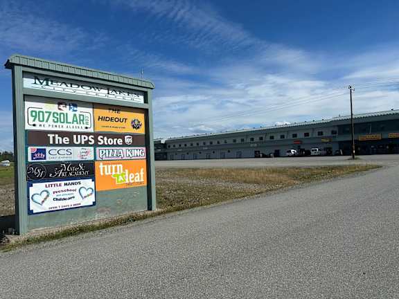 A signboard with various advertisements including 907 Solar, The Hideout, and The UPS Store.