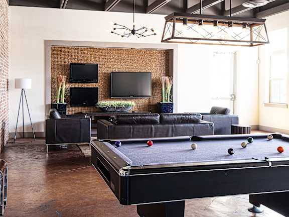 A pool table is in the middle of a room with a brick wall and a television  at Bristol Station Apartments, Carteret, New Jersey