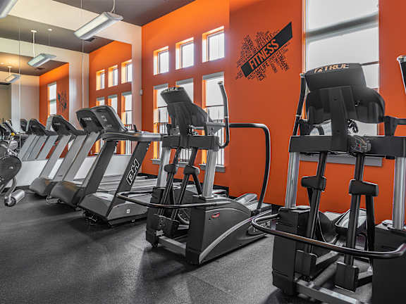 A gym with orange walls and treadmills  at Bristol Station Apartments, Carteret, New Jersey