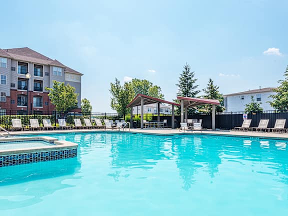 A swimming pool in a sunny day with chairs around it  at Bristol Station Apartments, Carteret, New Jersey