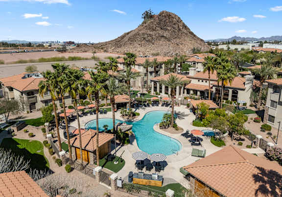 A large swimming pool surrounded by palm trees and buildings.