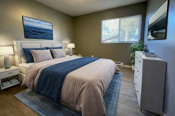 A bedroom with a large bed and a painting on the wall.