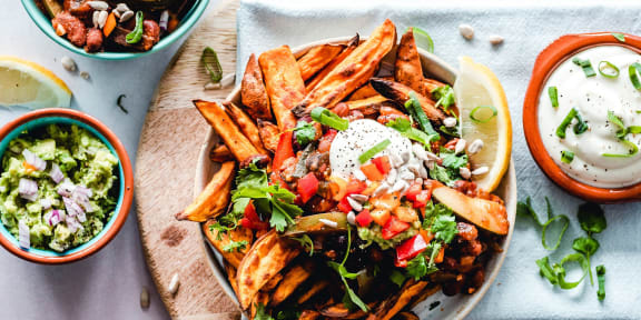 a bowl of fries with toppings on a wooden plate