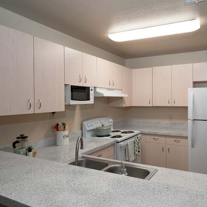 a kitchen with white cabinets and a sink and a refrigerator at The Fountains Apartments, Pensacola, Florida, 32514