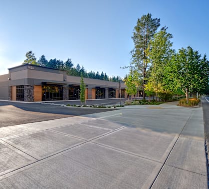 an empty parking lot in front of a building with trees
