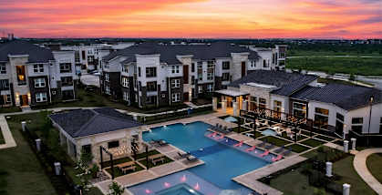 A beautiful sunset view of a swimming pool surrounded by apartment buildings.