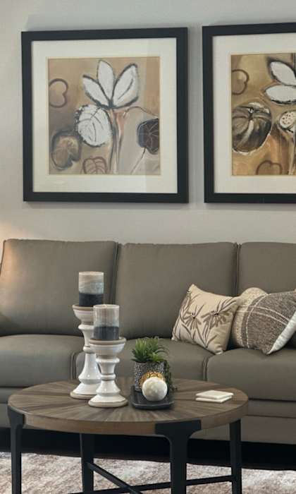 A living room with a grey couch, a coffee table, and two framed pictures on the wall.