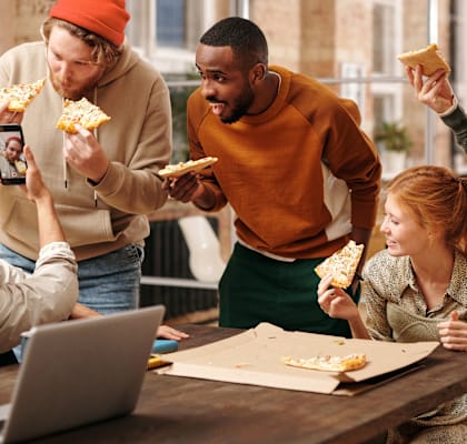 A group of people enjoying pizza together in a casual setting.