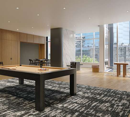 A shiny wooden pool table in a room with a black and white rug.