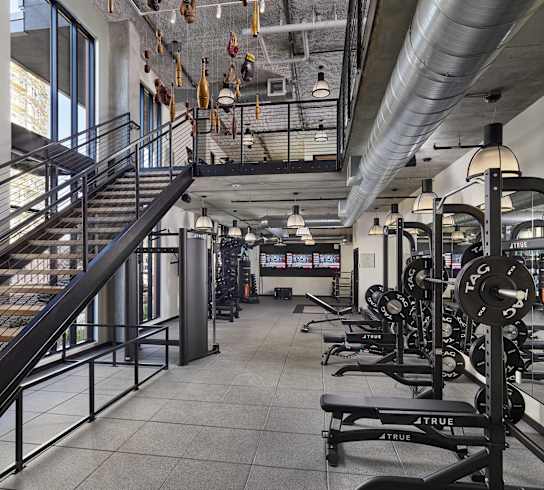 A gym with a staircase, weights, and exercise equipment.