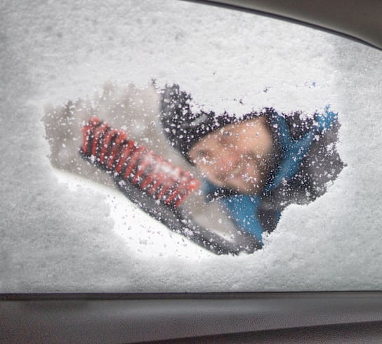 a person is seen through a car window covered in snow
