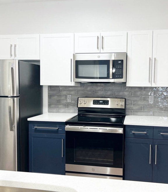 a kitchen with blue and white cabinets and stainless steel appliances
