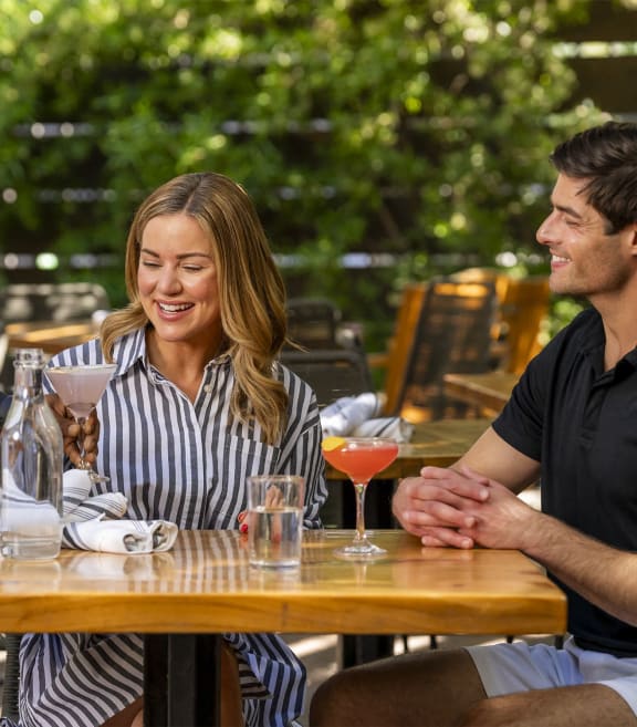 a man and a woman are seated at a wooden table in an outdoor settingat AVE Santa Clara, California, 95054