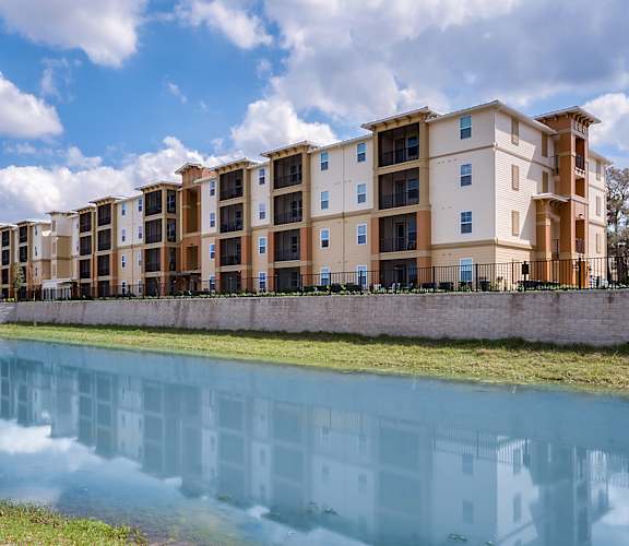 an image of an apartment complex with a lake in front of it