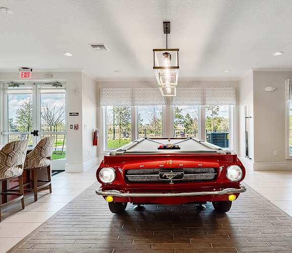 a pool table with a red car in the middle of the room