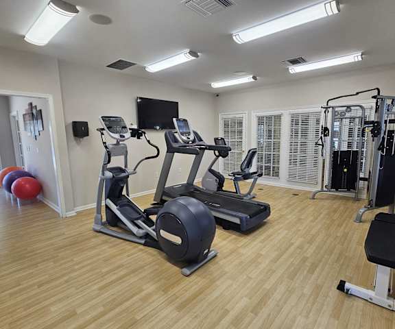 a gym with cardio equipment and a tv on the wall