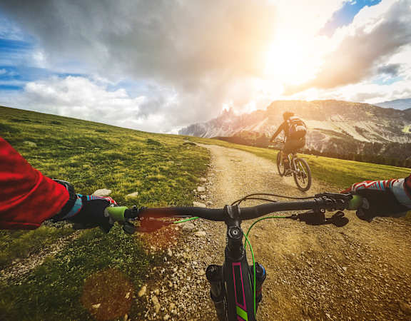 A person riding a bicycle on a dirt road in the mountains.