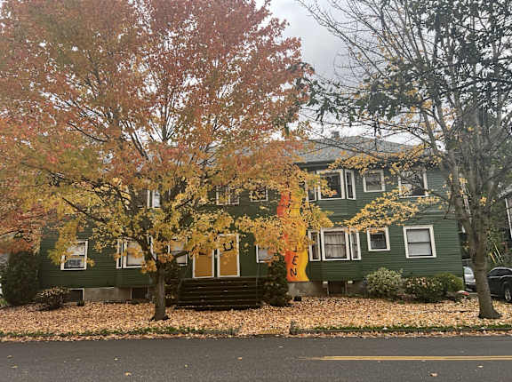 a green house with yellow and orange trees in front of it