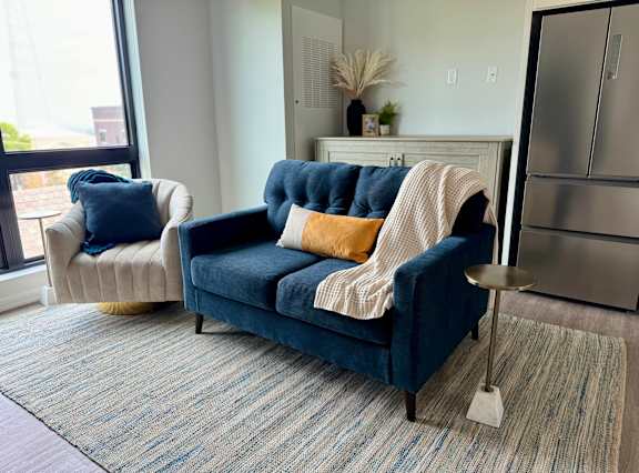 a living room with a blue couch and a chair with pillows