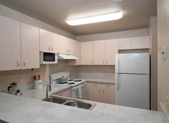 a kitchen with white cabinets and a sink and a refrigerator at The Fountains Apartments, Pensacola, Florida, 32514
