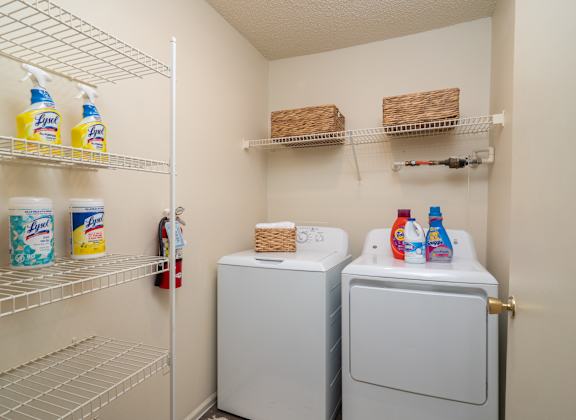 a laundry room with washer and dryer and a closet with shelves at The Fountains Apartments, Pensacola, Florida, 32514