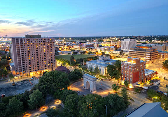 A cityscape at dusk with a large archway in the center.