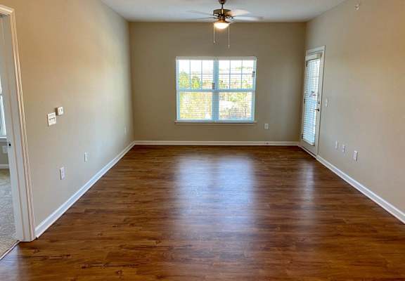 an empty living room with wooden floors and a window