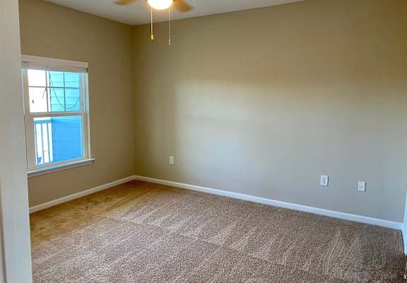 an empty living room with a ceiling fan and a window