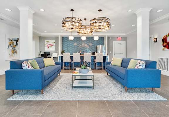 A spacious living room with blue couches and a glass coffee table.