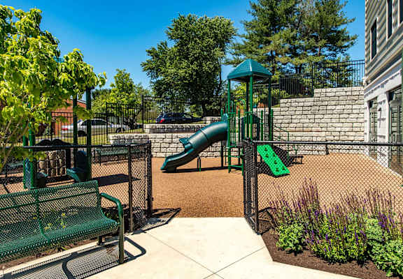 A playground with a green slide and a green bench.