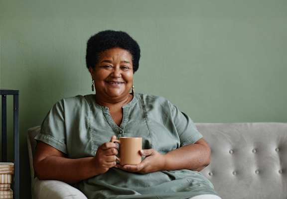 A woman is sitting on a couch holding a mug.