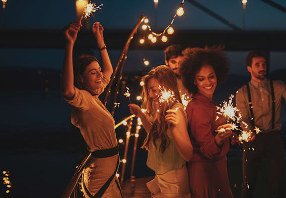 A group of people holding sparklers at night.