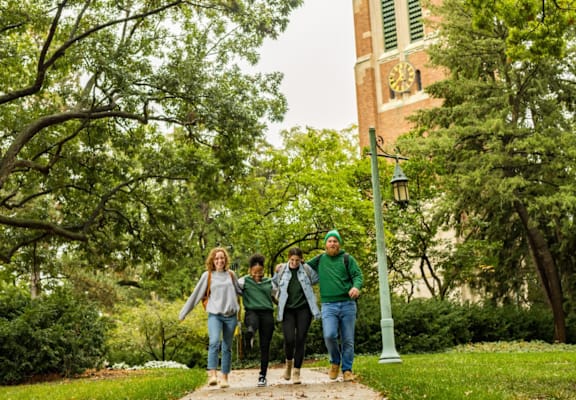 Four people walking on a path in a park.