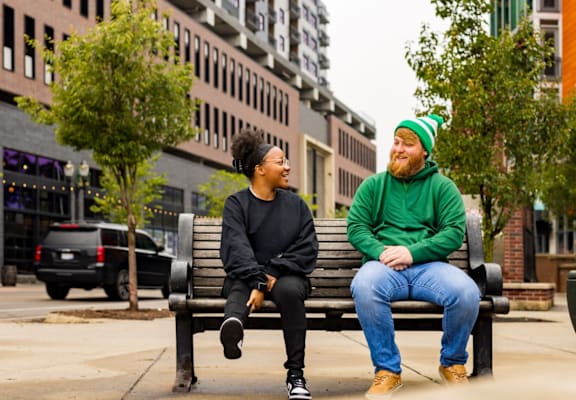 Two people sitting on a bench in a city setting.