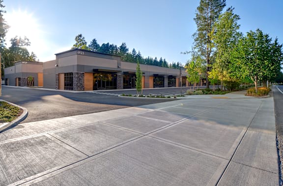an empty parking lot in front of a building with trees