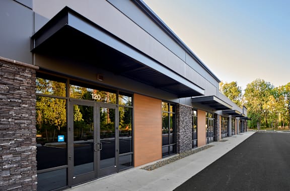 the exterior of a building with glass doors and a sidewalk