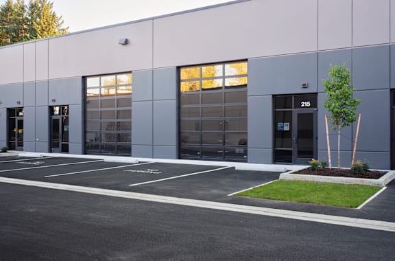 the exterior of a building with glass windows and a parking lot