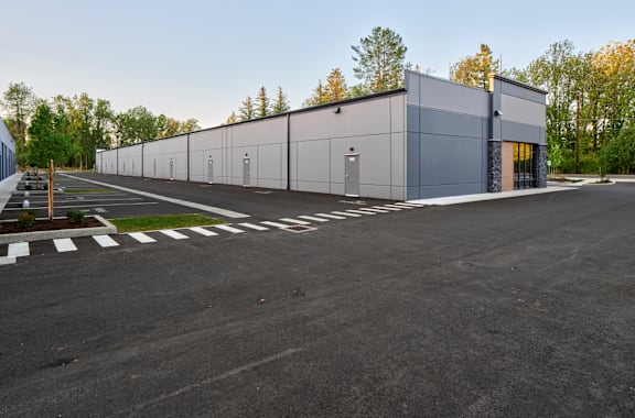 a large industrial building with a parking lot and trees
