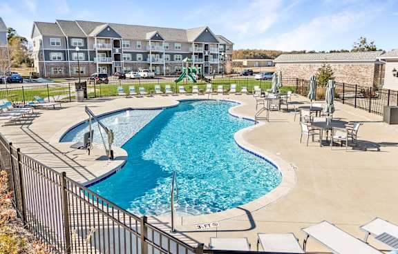 A large outdoor swimming pool surrounded by lounge chairs and buildings in the background at Echo Park at Perry Crossing Apartments, Indiana