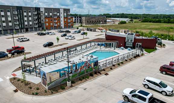 an aerial view of a parking lot with a pool and a building at Linc, Des Moines, IA 50309