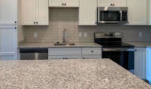 a kitchen with white cabinets, stainless steel appliances, and granite countertops