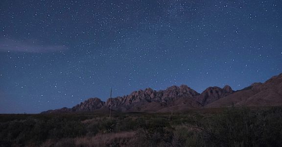 the night sky over the mountains in the desert
