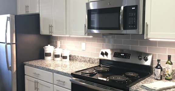 A kitchen with a black stove and white cabinets. at Vue on Medlock, Peachtree Corners, GA, 30092