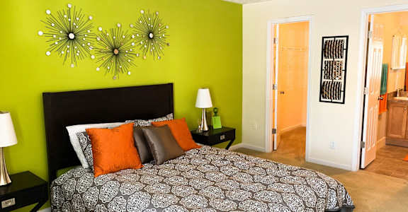 A bedroom with a patterned bedspread and a green wall.