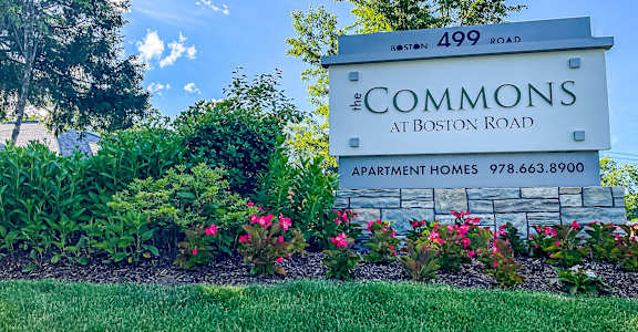 A sign for the Commons at Boston Road with flowers in the foreground.