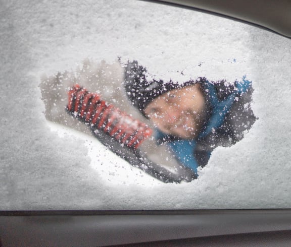 a person is seen through a car window covered in snow
